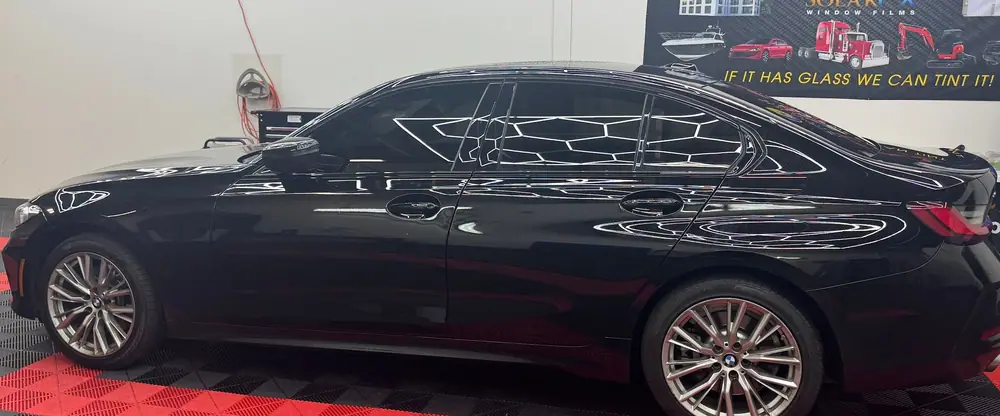 Black BMW sedan with tinted windows, hexagon lights reflecting in the glass